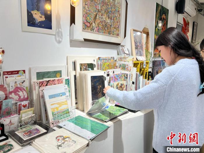 圖為藝術(shù)品商店內(nèi)，顧客挑選插畫作品?！＄婌?攝