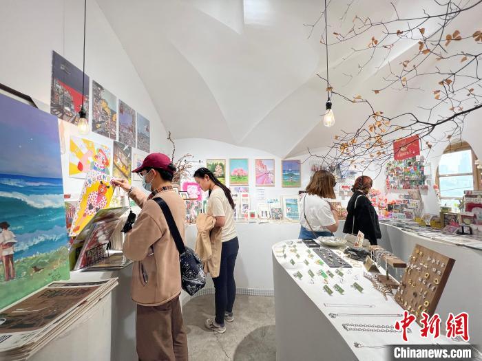 圖為藝術(shù)品商店內(nèi)，顧客挑選插畫作品?！＄婌?攝