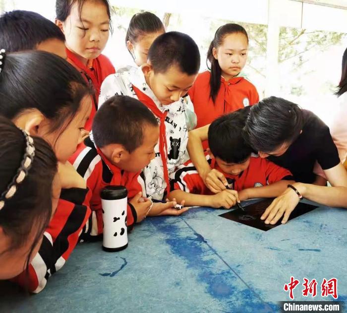 圖為朱增平(右一)教學(xué)生創(chuàng)作鍥金畫。(資料圖) 受訪者供圖