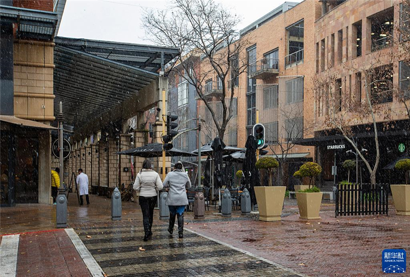 7月10日，在南非約翰內斯堡一處商業(yè)區(qū)，人們在雪中行走。新華社記者 張譽東 攝