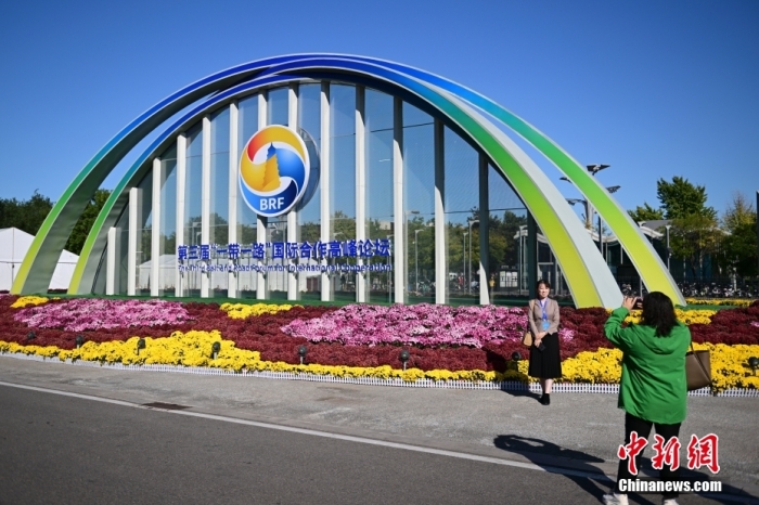 10月15日，北京，工作人員在國家會議中心外的第三屆“一帶一路”國際合作高峰論壇景觀布置前拍照留念。當(dāng)日，位于國家會議中心的第三屆“一帶一路”國際合作高峰論壇新聞中心啟動試運(yùn)行。據(jù)悉，第三屆“一帶一路”國際合作高峰論壇將于10月17日至18日在北京舉行。<a target='_blank' href='/'><p  align=