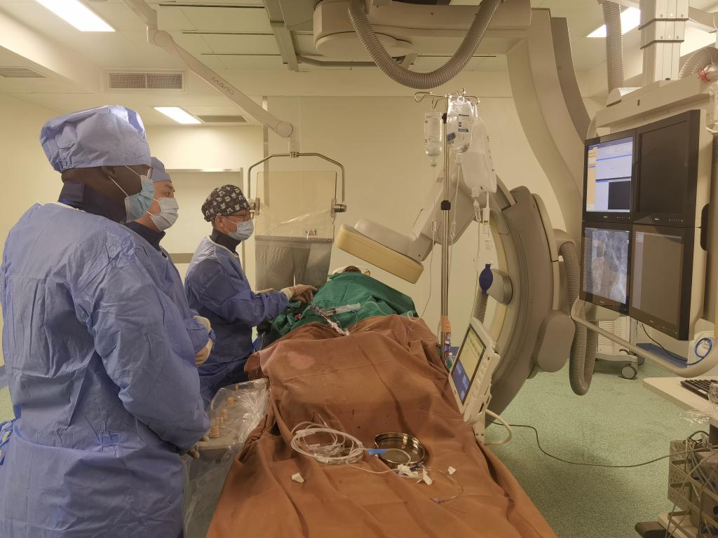 中國第29批援幾內(nèi)亞醫(yī)療隊隊員、首都醫(yī)科大學(xué)附屬北京天壇醫(yī)院心內(nèi)科副主任醫(yī)師王汝朋（右一）正在給患者做手術(shù)。（北京天壇醫(yī)院供圖）