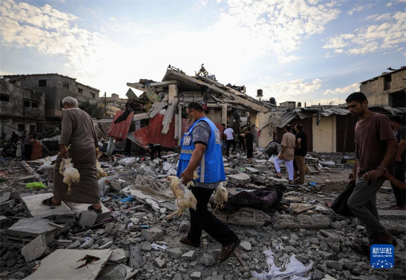 10月27日，在加沙地帶南部城市汗尤尼斯，人們經(jīng)過(guò)以軍襲擊后的房屋廢墟。