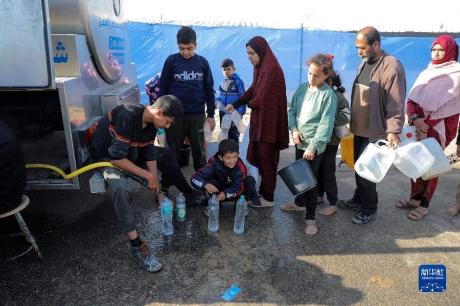 12月8日，在加沙地帶南部城市拉法一處臨時營地內(nèi)，人們排隊打水。新華社發(fā)（里澤克·阿卜杜勒賈瓦德 攝）