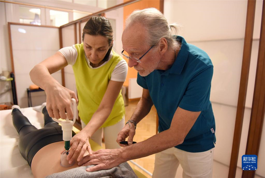 12月12日，在奧地利維也納，科格勒醫(yī)生（右）和助手在為病人進行拔罐治療。新華社記者 賀燦鈴 攝