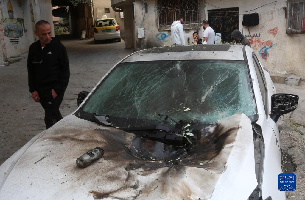 12月17日，在約旦河西岸城市圖勒凱爾姆附近的一處難民營，人們查看在沖突中損毀的車輛。新華社發(fā)（尼達爾·艾仕塔耶?dāng)z）