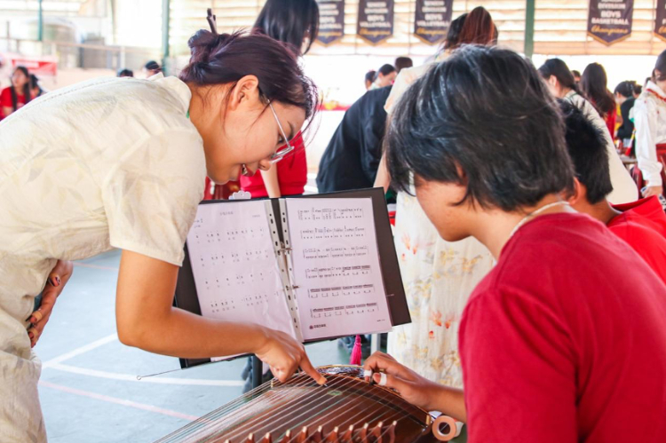 志愿者教師指導(dǎo)學(xué)生彈奏古箏?；顒又鬓k方供圖