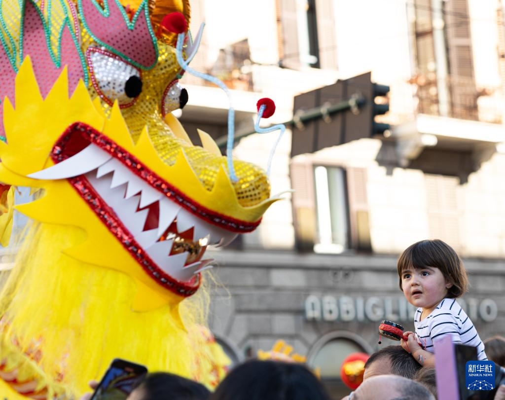 2月18日，在意大利羅馬，一名小朋友在彩妝巡游上觀看舞龍。新華社記者 李京 攝