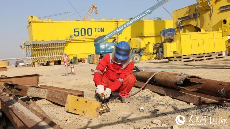 工人正在龍門吊吊裝現(xiàn)場切割金屬件。人民網(wǎng)記者管克江攝