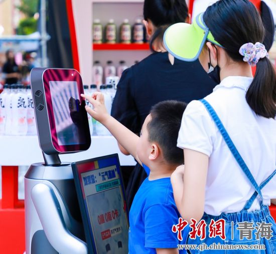 圖為一名小朋友正在和機器人“志愿者”進行互動。 沐聞 攝