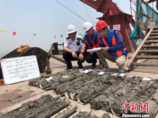 圖為勘察設(shè)計人員與海事局工作人員查看巖芯情況。　魏震 攝