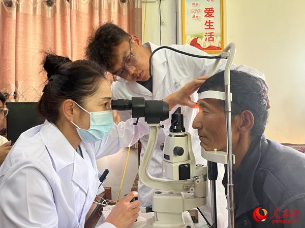 王紅英（左）和團(tuán)隊(duì)成員為達(dá)熱村村民檢查眼睛。人民網(wǎng)記者 杜燕飛攝
