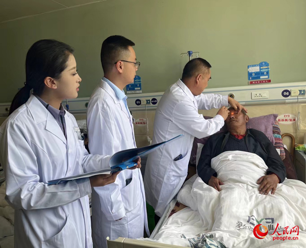 董光明（左三）帶領(lǐng)醫(yī)生對(duì)患者進(jìn)行術(shù)前檢查。人民網(wǎng)記者 杜燕飛攝