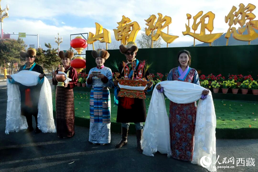 扎西曲登社區(qū)的居民在“山南歡迎您”標(biāo)志前，手持潔白哈達(dá)和切瑪，列隊(duì)迎接來(lái)自區(qū)內(nèi)外的游客，用最隆重的禮儀開(kāi)啟一場(chǎng)沉浸式藏歷新年民俗體驗(yàn)之旅。人民網(wǎng)記者 吳雨仁攝