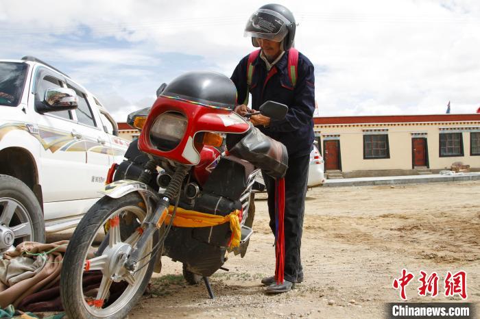 圖為白瑪準(zhǔn)備騎摩托車巡湖?！≮w朗 攝