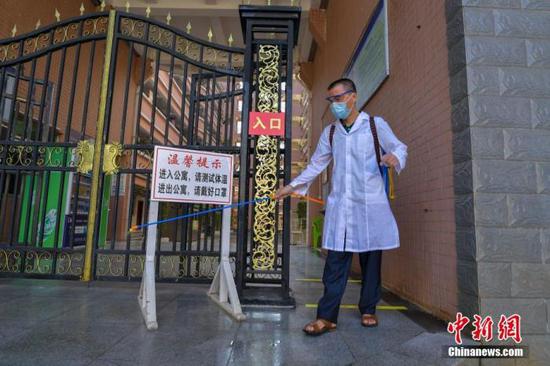 資料圖：海口經(jīng)濟(jì)學(xué)院的工作人員在學(xué)生宿舍樓入口消毒。 中新社記者 駱云飛 攝