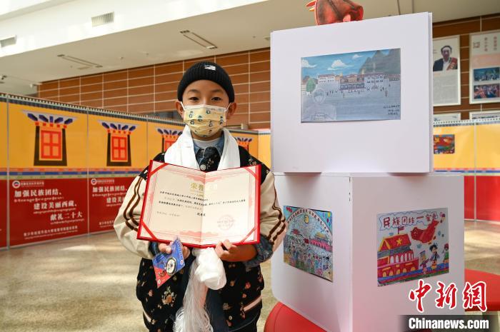 圖為一名獲獎(jiǎng)學(xué)生與自己的繪畫作品合影?！≮w朗 攝