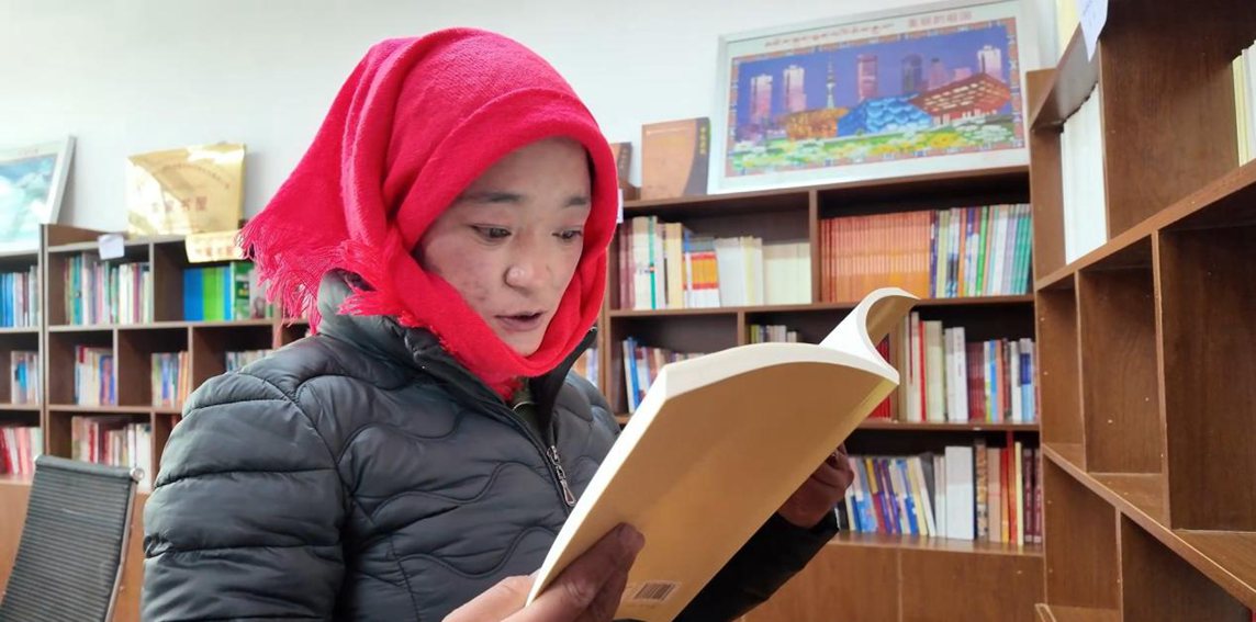一名婦女正在認(rèn)真閱讀書籍。申扎縣融媒體中心供圖