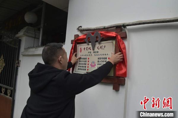 桂溪鎮(zhèn)渭溝村政府工作人員為“十星級文明戶”掛上牌匾。　楊勇 攝