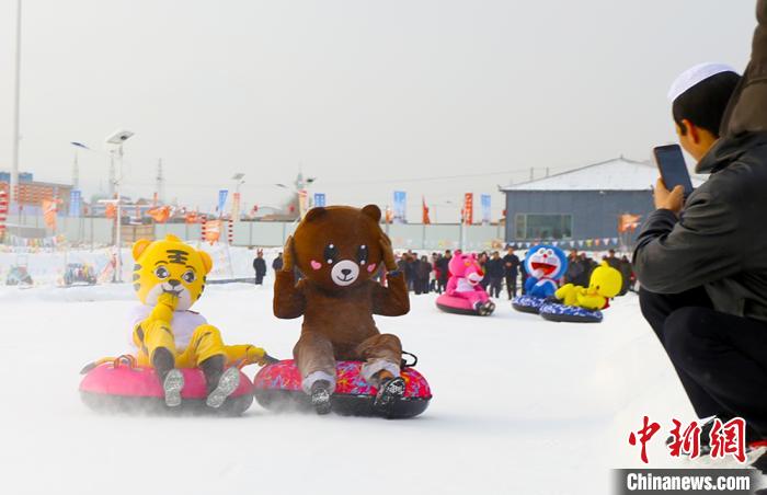 圖為臨夏市南龍鎮(zhèn)馬家莊村舉辦的鄉(xiāng)村文化旅游節(jié)上，游客穿著卡通服裝在體驗(yàn)雪上飛碟項(xiàng)目。近年來，臨夏州形成了“春賞花、夏避暑、秋摘果、冬玩雪”的全季節(jié)旅游產(chǎn)品體系。(資料圖) 高展 攝