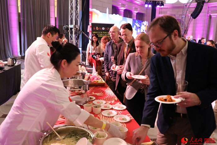 當?shù)貢r間3月7日晚，華盛頓聯(lián)合車站廣場舉行駐美使團“使館主廚挑戰(zhàn)賽”。圖為當?shù)孛癖娫谥袊古_前體驗中國美食。人民網(wǎng)記者 李志偉攝
