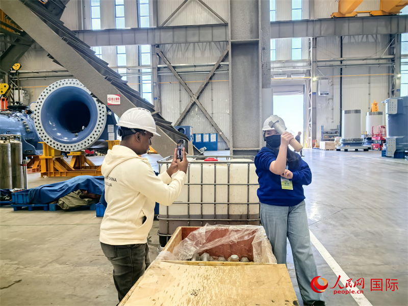 外媒記者掂量廠房內的巨型螺栓。人民網 楊春燕攝