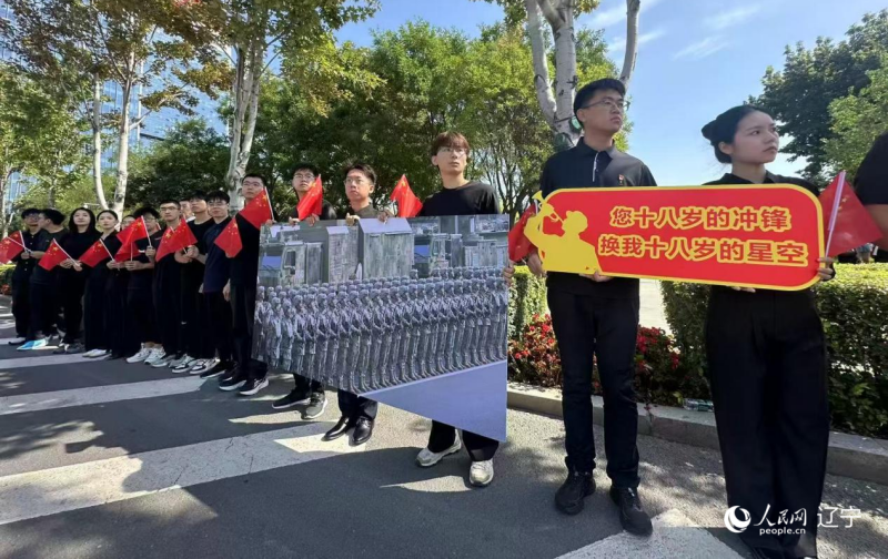 沈陽市人民廣場上，大學(xué)生們手持閱兵的圖片，告慰英烈。人民網(wǎng)記者 周頌雪攝