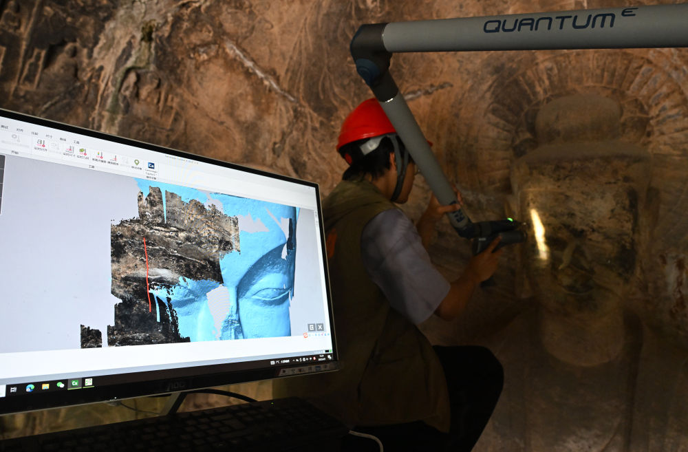 2025年4月9日，武漢大學(xué)文化遺產(chǎn)智能計(jì)算實(shí)驗(yàn)室團(tuán)隊(duì)成員在魏字洞使用關(guān)節(jié)臂掃描儀對(duì)佛像進(jìn)行數(shù)字化掃描。圖片來(lái)源新華社