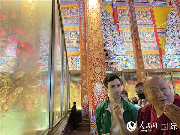 7月25日，省級(jí)非物質(zhì)文化遺產(chǎn)項(xiàng)目塔爾寺酥油花的代表性傳承人朋措堅(jiān)參（右）在塔爾寺酥油花館講解酥油花的制作過程。人民網(wǎng) 謝瑩攝