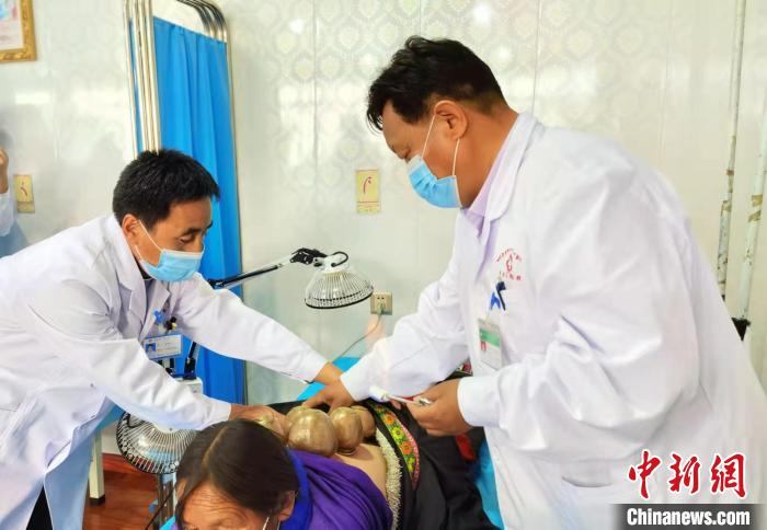 圖為看照加手把手帶徒弟加老(左一)進(jìn)行拔罐療法。　張婧 攝