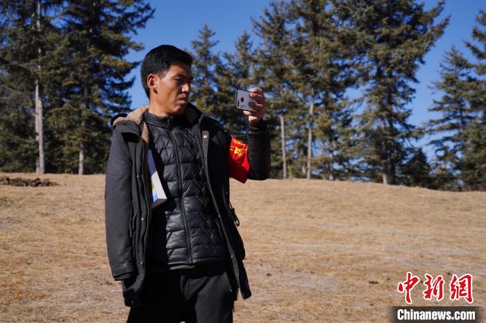 圖為桑杰加進行巡查并拍照記錄?！●R銘言 攝