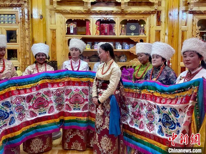 圖為女性展示村民自發(fā)繡制的“百米五彩哈達(dá)”?！±钣穹?攝