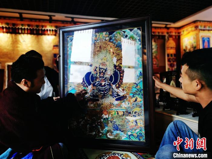 圖為久美尖措(左)與徒弟們展示唐卡作品?！?zhí)砀?攝
