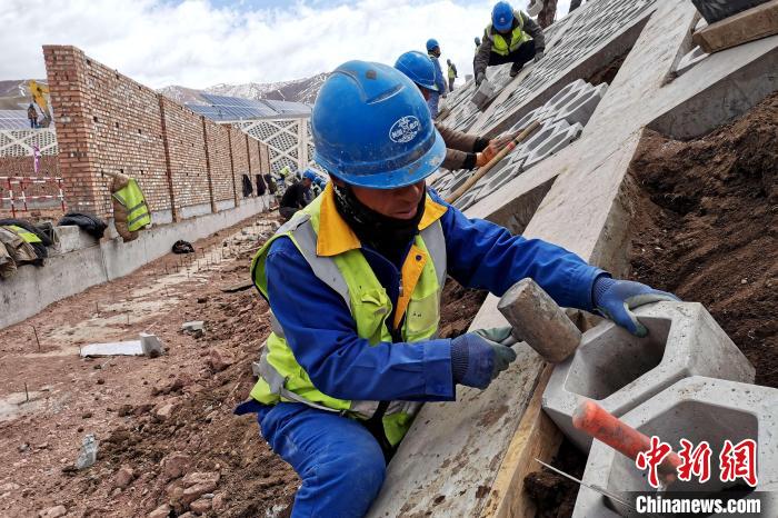 圖為光伏發(fā)電項(xiàng)目施工區(qū)工人在護(hù)坡鋪設(shè)空心磚。　李雋 攝