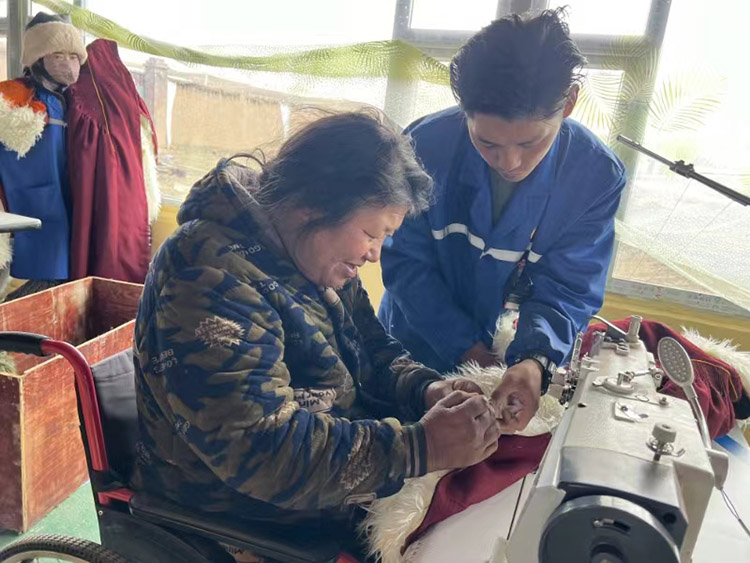扎西奪爾登幫助殘疾員工裁剪。阿壩州文明辦供圖