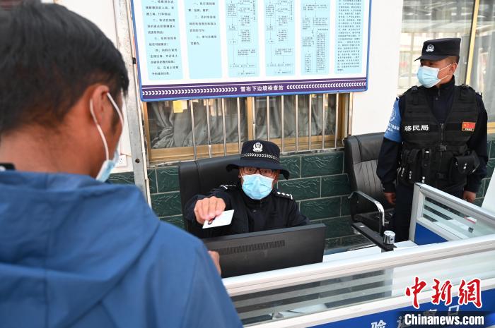 圖為移民管理警察登記完身份信息后將證件歸還給行人?！≮w朗 攝