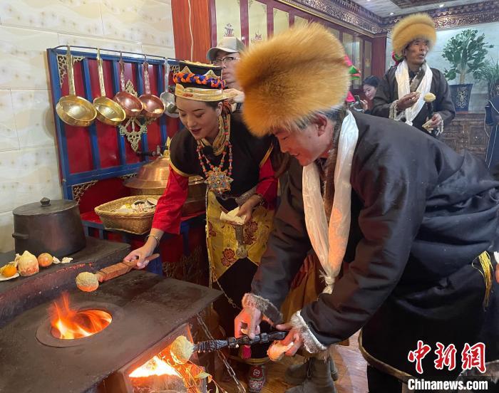 圖為人們在火上烤節(jié)日美食“結(jié)達(dá)”?！∪轿木?攝