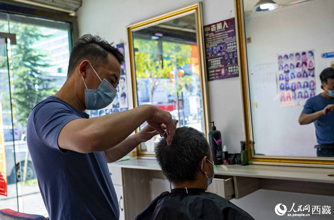 理發(fā)店老板為顧客理發(fā)。次仁羅布 攝