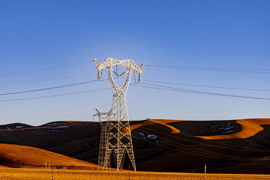 阿里地區(qū)的曠野上，電力鐵塔在夕陽(yáng)下熠熠生輝。