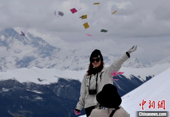 圖為5月14日，游客在西藏林芝色季拉山觀景臺拋灑“隆達”(風馬旗，藏族民眾的一種祈福方式)?！±盍?攝
