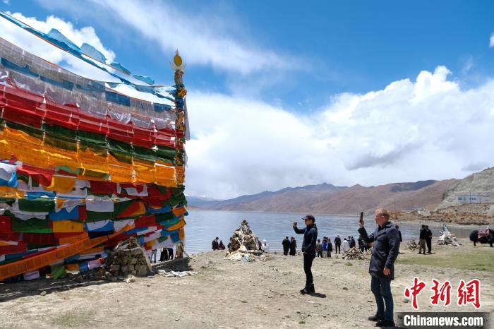 進藏參訪嘉賓在羊湖畔拍攝經(jīng)幡。　江飛波 攝