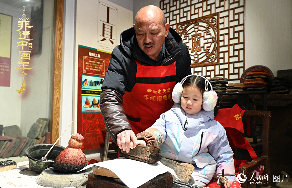 2025年1月27日，河南開封朱仙鎮(zhèn)木版年畫藝人尹國法指導小朋友研習年畫印制技藝。朱仙鎮(zhèn)木版年畫源自漢唐壁畫藝術(shù)，是中國木版年畫的鼻祖。2006年5月20日，朱仙鎮(zhèn)木版年畫經(jīng)國務(wù)院批準列入第一批國家級非物質(zhì)文化遺產(chǎn)名錄。人民網(wǎng)記者 王玉興攝