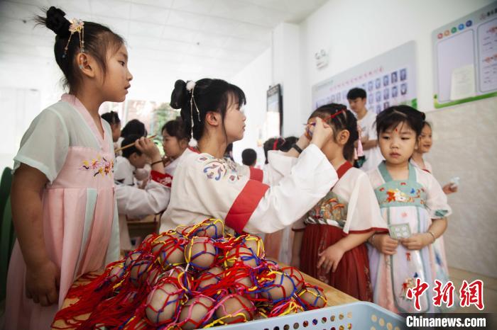 圖為幼兒園的老師們穿上漢服為小朋友們戴上彩蛋，寓意著幸福安康?！《^生 攝