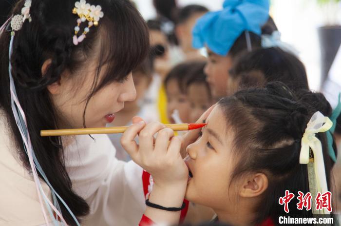 圖為老師在孩子們額頭上點(diǎn)上雄黃，驅(qū)邪辟禍?！《^生 攝